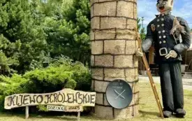 Sołectwo Kijewo Kr&oacute;lewskie. Witacz przedstawiający komin na kt&oacute;rym znajduje się gniazdo z bocianami. Obok stoi kominiarz oraz zamieszczony jest guzik szcześcia