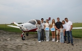 Nagrodzone absolwentki klasy 8 z rodzinami przed samolotem