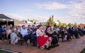 Publiczność siedząca na ławka i bijąca brawa